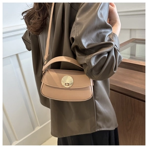 Detail view of stylish beige leather underarm bag with gold shell buckle worn by a model