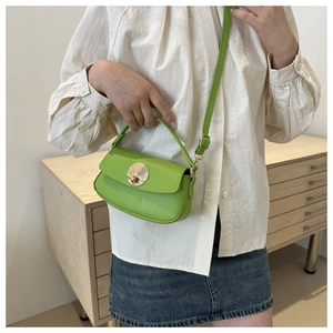 Detail of bright green crossbody bag with gold shell buckle and adjustable shoulder strap