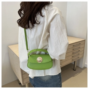 Model wearing a bright green patent leather shoulder bag with a large gold shell buckle