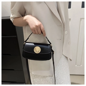 Detail of black matte underarm bag featuring a gold shell-shaped twist lock buckle