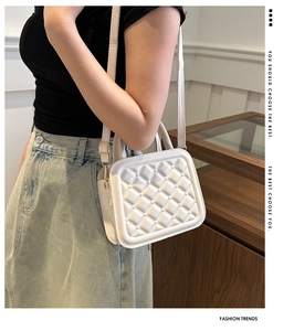 Detailed macro view of white quilted crossbody bag featuring elegant gold-tone hardware detail