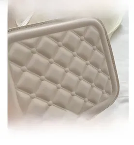 Close-up of beige quilted crossbody bag with detailed diamond stitching and leather texture