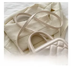Close-up of beige quilted crossbody bag with adjustable strap on a neutral blazer
