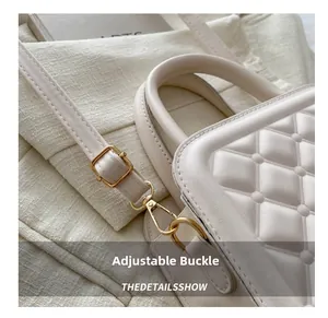 Detailed macro shot of a golden adjustable buckle on a beige quilted leather handbag