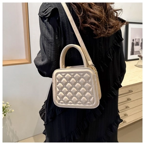 Detailed view of beige quilted mini square bag with top handle and crossbody strap