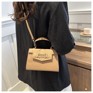 Modella che indossa una borsa a tracolla beige chic con eleganti dettagli in catena d'oro
