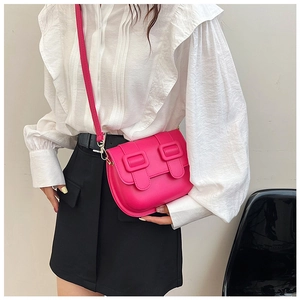 Close-up of rose pink crossbody bag with dual decorative buckles worn with white shirt