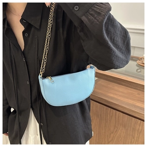 Light blue crescent shoulder bag with gold chain strap shown on a black shirt