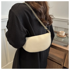 Detailed macro view of cream saddle bag with lychee texture and gold metal chain strap