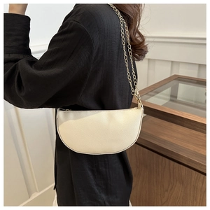 Detail of beige lychee textured crescent bag with gold chain strap on model