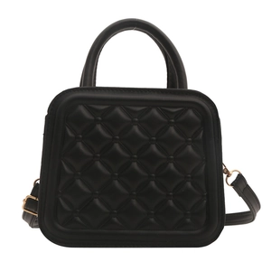 Classic black quilted crossbody bag with top handle and gold hardware on white background