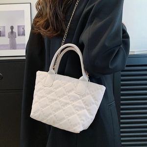 Elegante borsa a secchiello trapuntata bianca con catena d'oro indossata con un blazer