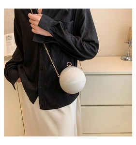 Elegant white marble sphere bag with gold circular handle and crossbody chain detail