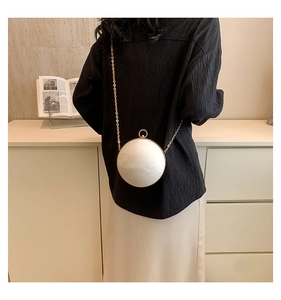 Detail view of pearl white marble texture spherical bag with golden chain strap