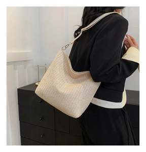 Détail du sac hobo tissé crème avec bandoulière réglable et boucle dorée sur modèle