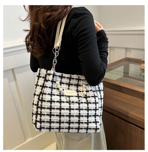 Detail of checkered tote bag featuring a pearl chain handle and leather fashion label