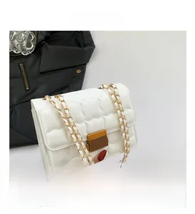 Detail of white quilted handbag featuring gold twist lock and dual chain straps