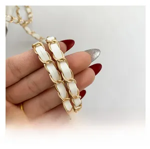 Detail of the white leather woven with gold metal chain strap on a stylish crossbody bag