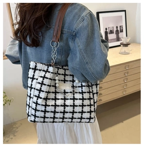Detail of checkered tweed tote bag featuring pearl chain charm and leather strap
