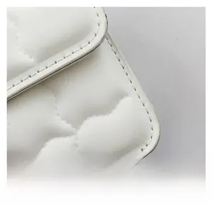 Detail of white quilted leather texture and precision stitching on the crossbody flap bag