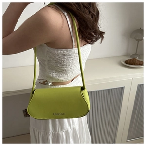 Gros plan du sac porté épaule en cuir vert avec lettrage Fashion sur tenue blanche