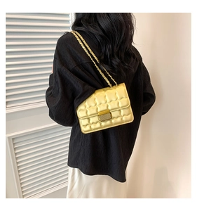 Sac bandoulière jaune matelassé porté par un mannequin sur un fond minimaliste