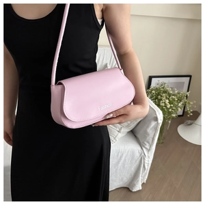 Détail du sac à bandoulière en cuir rose clair avec logo Fashion porté par un mannequin