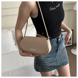 Détail du sac sous le bras en cuir beige mat avec typographie Fashion et rabat élégant