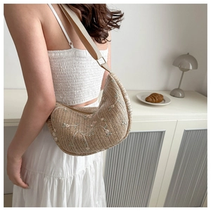 Close-up of beige woven shoulder bag with floral embroidery and wide canvas strap