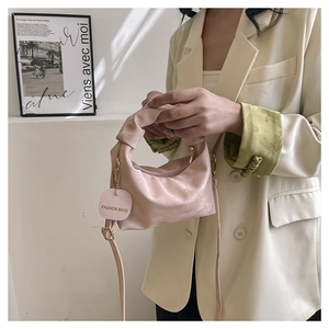 Detail of pink pleated cloud bag featuring round fashion tag and slim shoulder strap