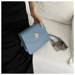 Détail du sac à bandoulière en cuir bleu clair avec boucle dorée à motif grec