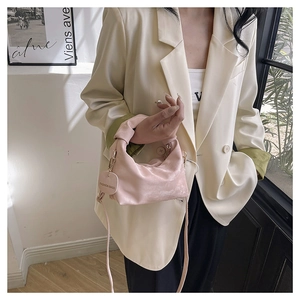 Detail shot of pink velvet dumpling bag with knot handle and adjustable strap worn on outfit