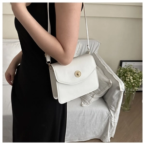 Détail du sac à bandoulière blanc avec boucle dorée élégante en relief sur le rabat
