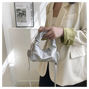 Detail of silver pleated cloud bag featuring knotted handle and fashion brand tag