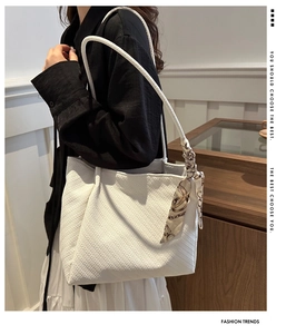 Detail of white tote bag featuring 3D knitted wave texture and floral silk scarf charm