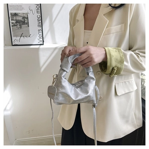 Detail of silver pleated dumpling bag with knotted handle and elegant metallic texture finish