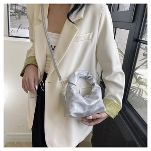 Detailed view of silver pleated dumpling bag with metallic sheen and ruffled handle texture