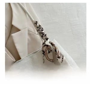 Detail showing white woven texture tote bag with vintage print silk scarf on handle