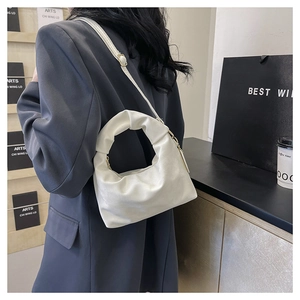 Close-up of white ruched crossbody bag with shoulder strap on a modern interior background