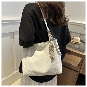 Close-up of white tote bag with textured fabric and silk scarf on the shoulder strap