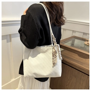 Detail of white textured fabric tote bag featuring a decorative printed silk scarf on the strap