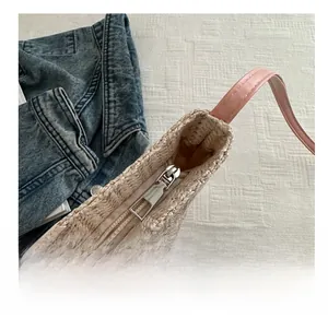 Close-up of pink leather strap and smooth silver metal zipper on a beige straw tote bag