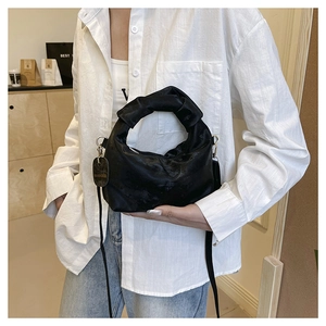 Detail of black ruched velvet handbag with knotted handle and adjustable shoulder strap