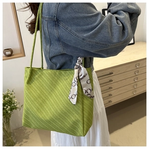 Detail of avocado green woven tote bag with silk scarf on handle, casual shoulder bag