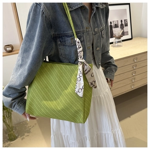 Detail of green tote bag with woven texture and decorative black and white chain scarf