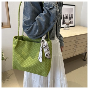 Detail of green tote bag with herringbone texture and silk scarf handle decoration