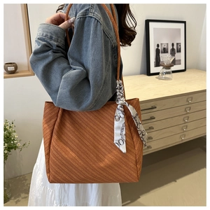 Detail of large tote bag in orange brown with geometric texture and decorative silk scarf