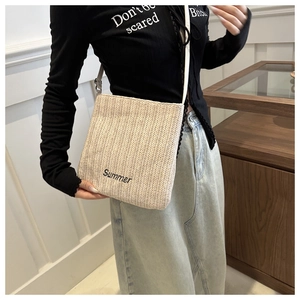 Detail of high-quality woven straw texture and black Summer embroidery on a beige tote bag