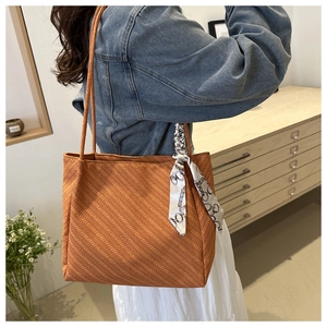 Orange-brown textured tote bag with printed silk scarf detail on shoulder model