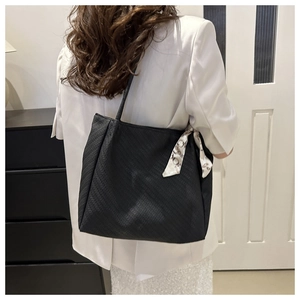 Detail of black tote bag with chevron texture and printed silk scarf on handle
